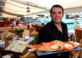 Grk milioner u taverni na plaži sam uslužuje goste