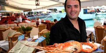 Grk milioner u taverni na plaži sam uslužuje goste